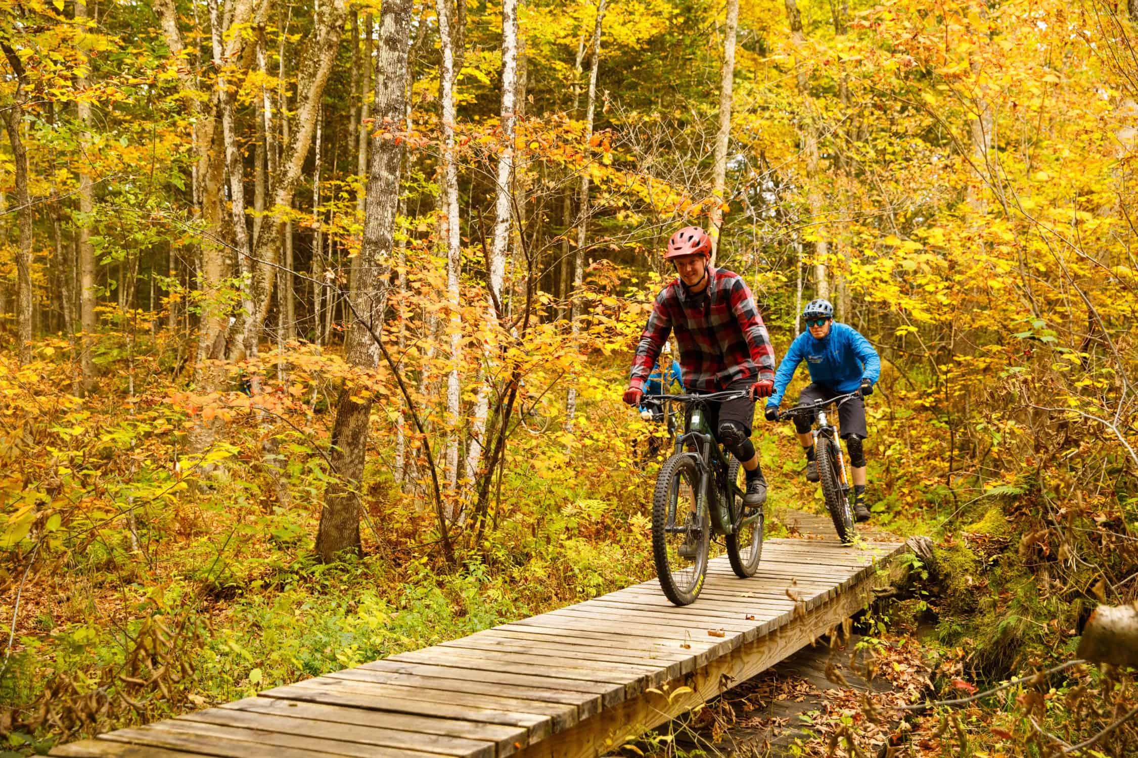 Two students ride their bikes on the campus trails