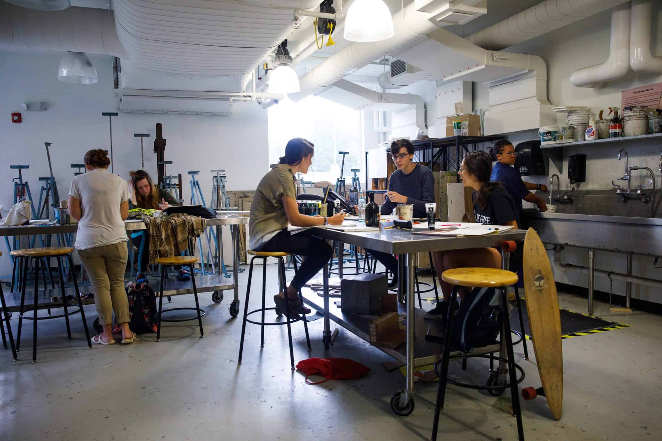 Students sit on stools in an art studio