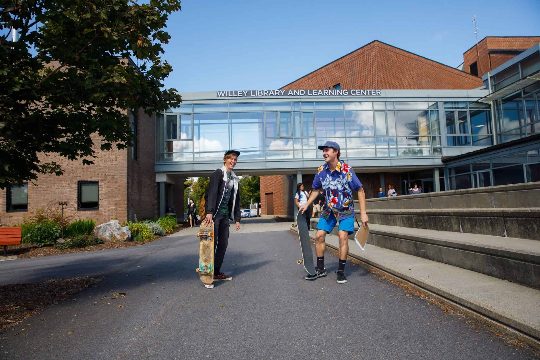 Two students with skateboards outside the Wiley library