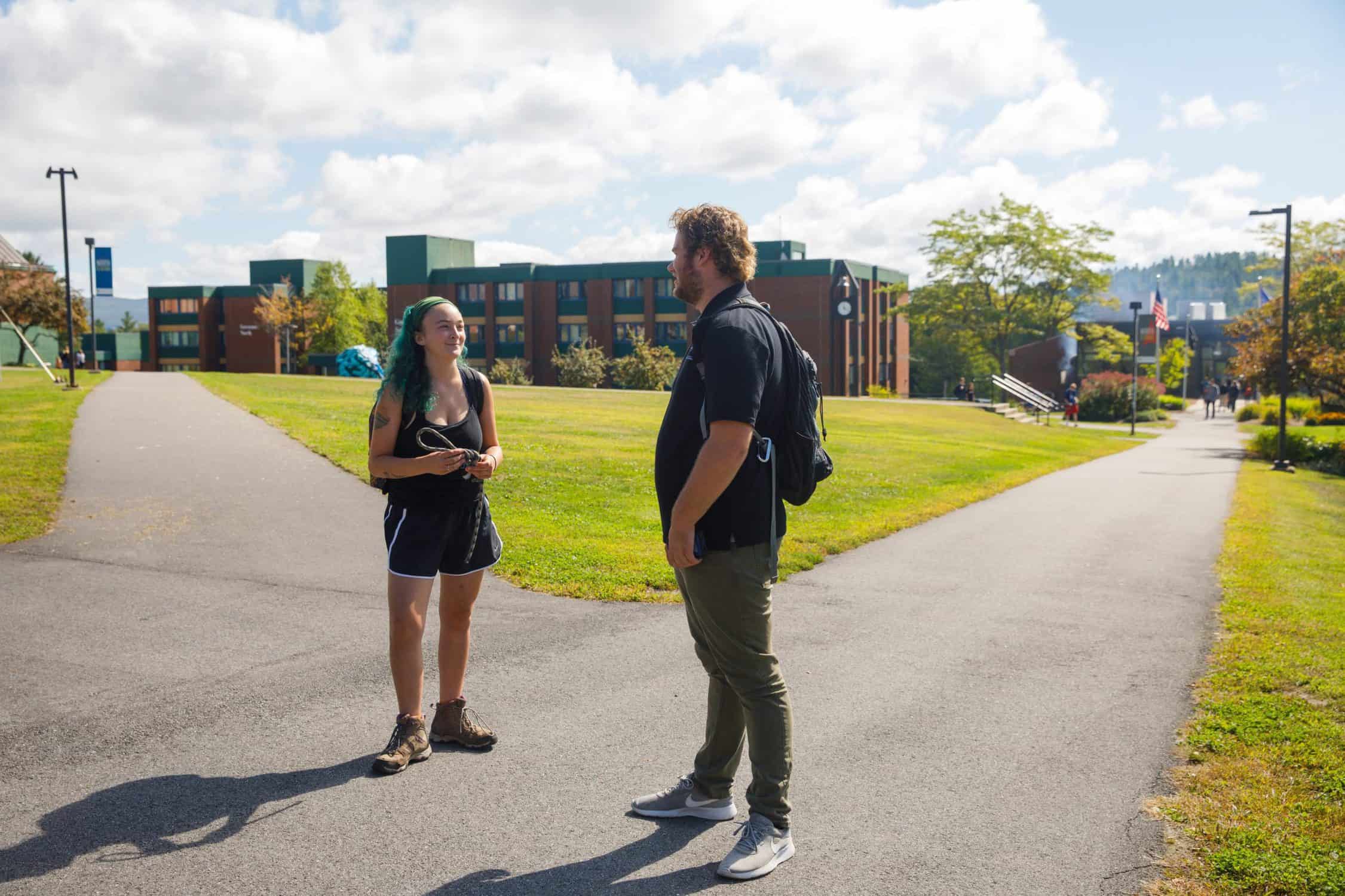 Two students stand outside talking