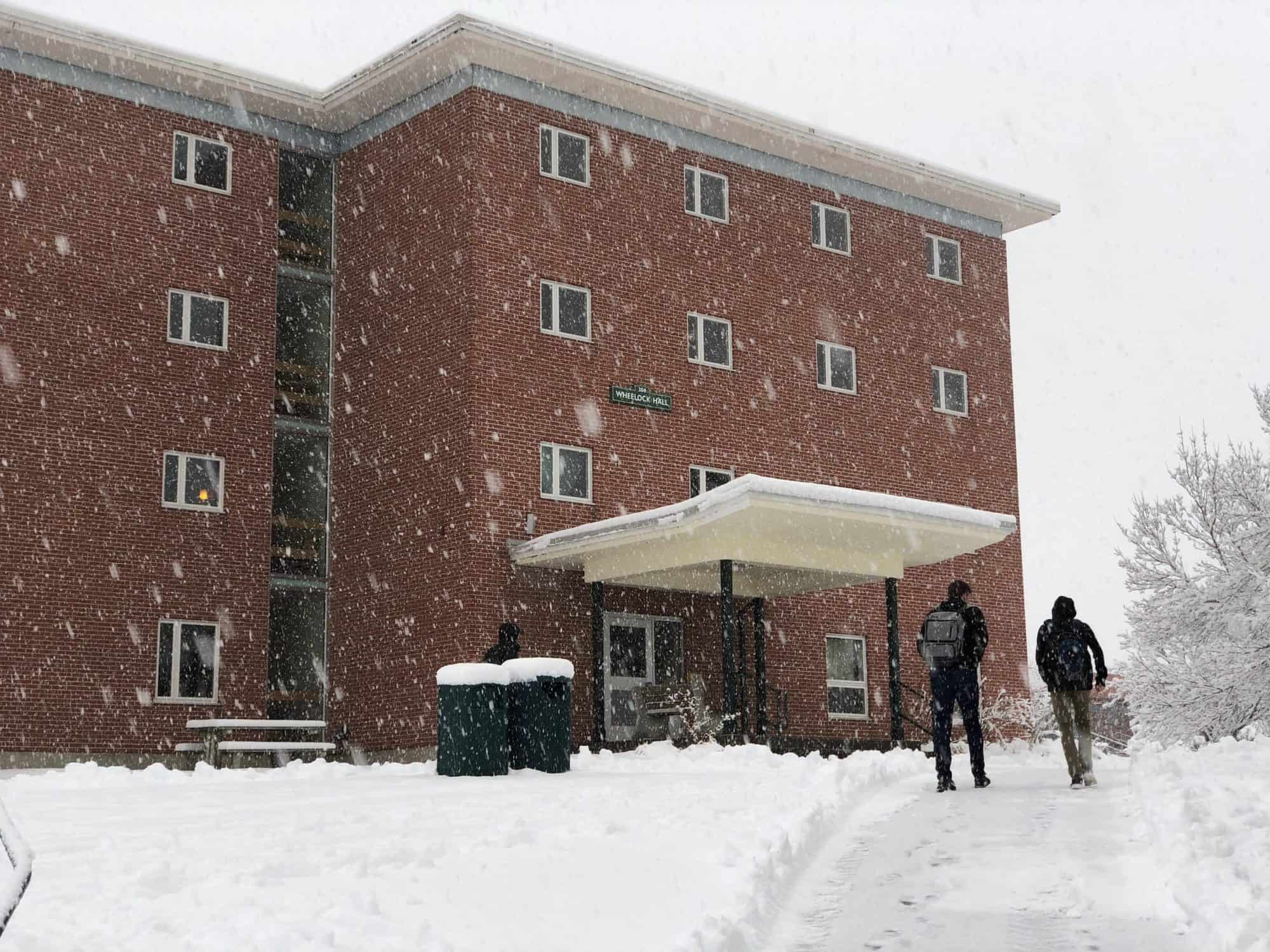 Students walk by the Wheelock residence hall on a snowy day