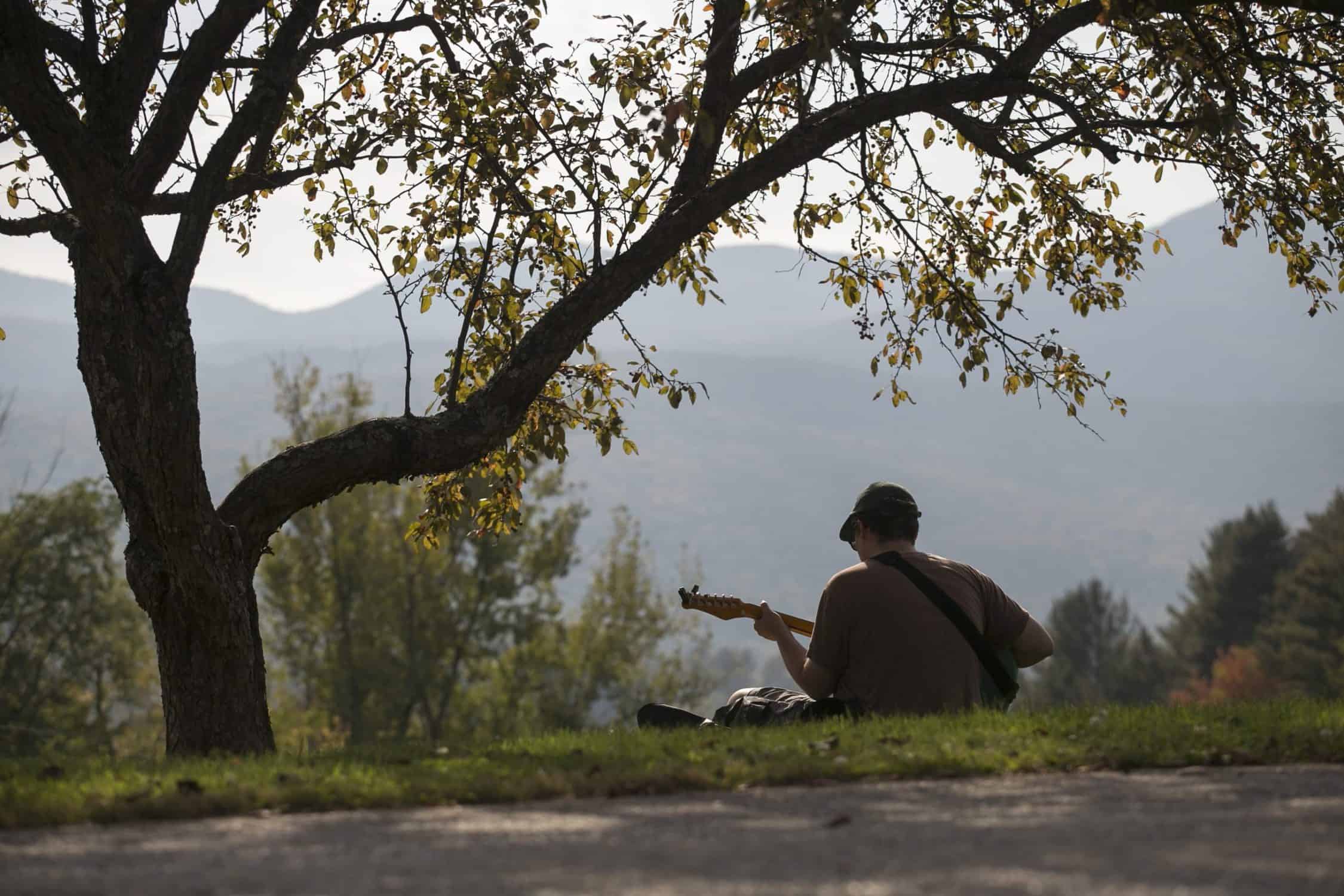 Student plays guitar looking toward the mountains