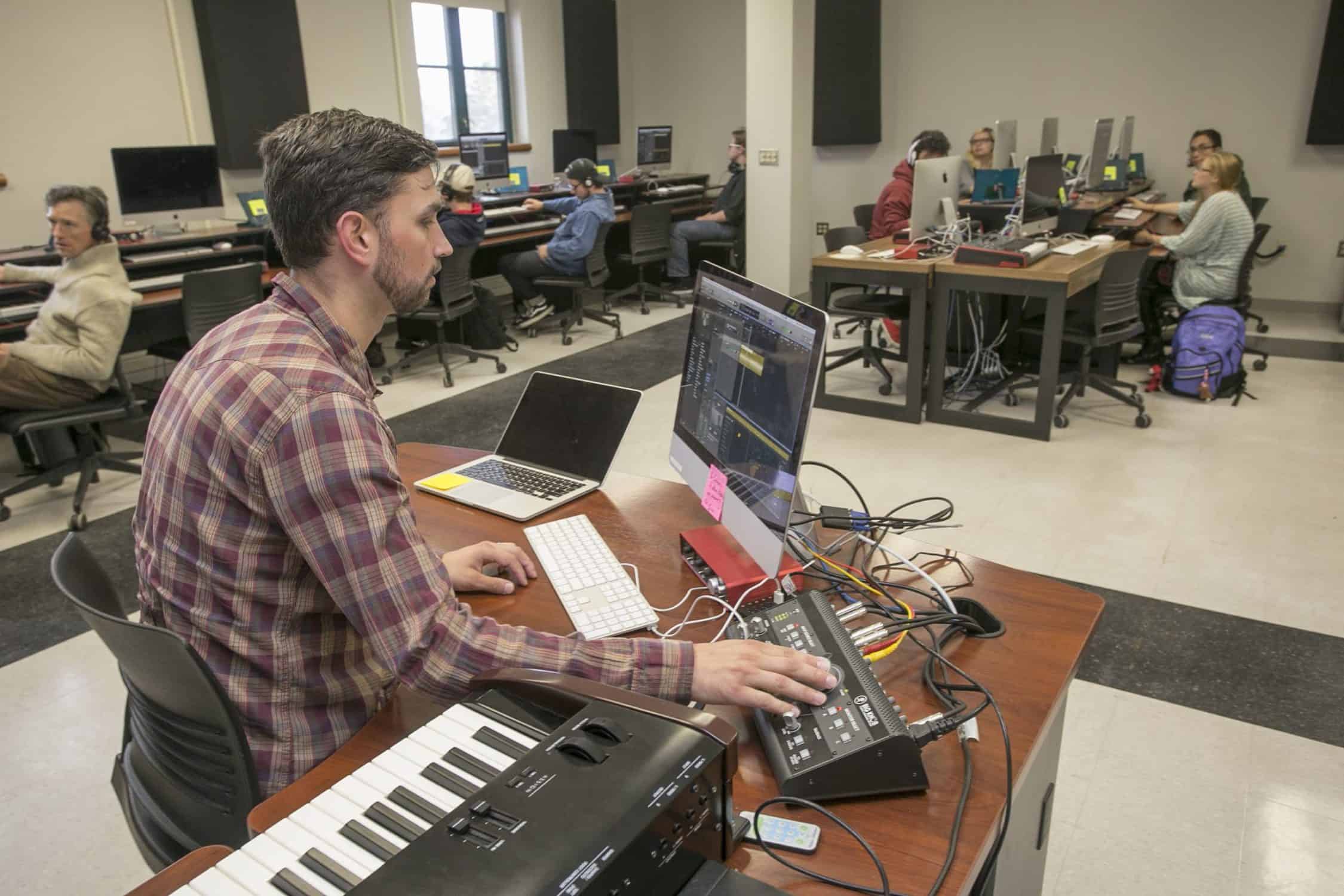 Professor sits in the MIDI lab demonstrating the software to students