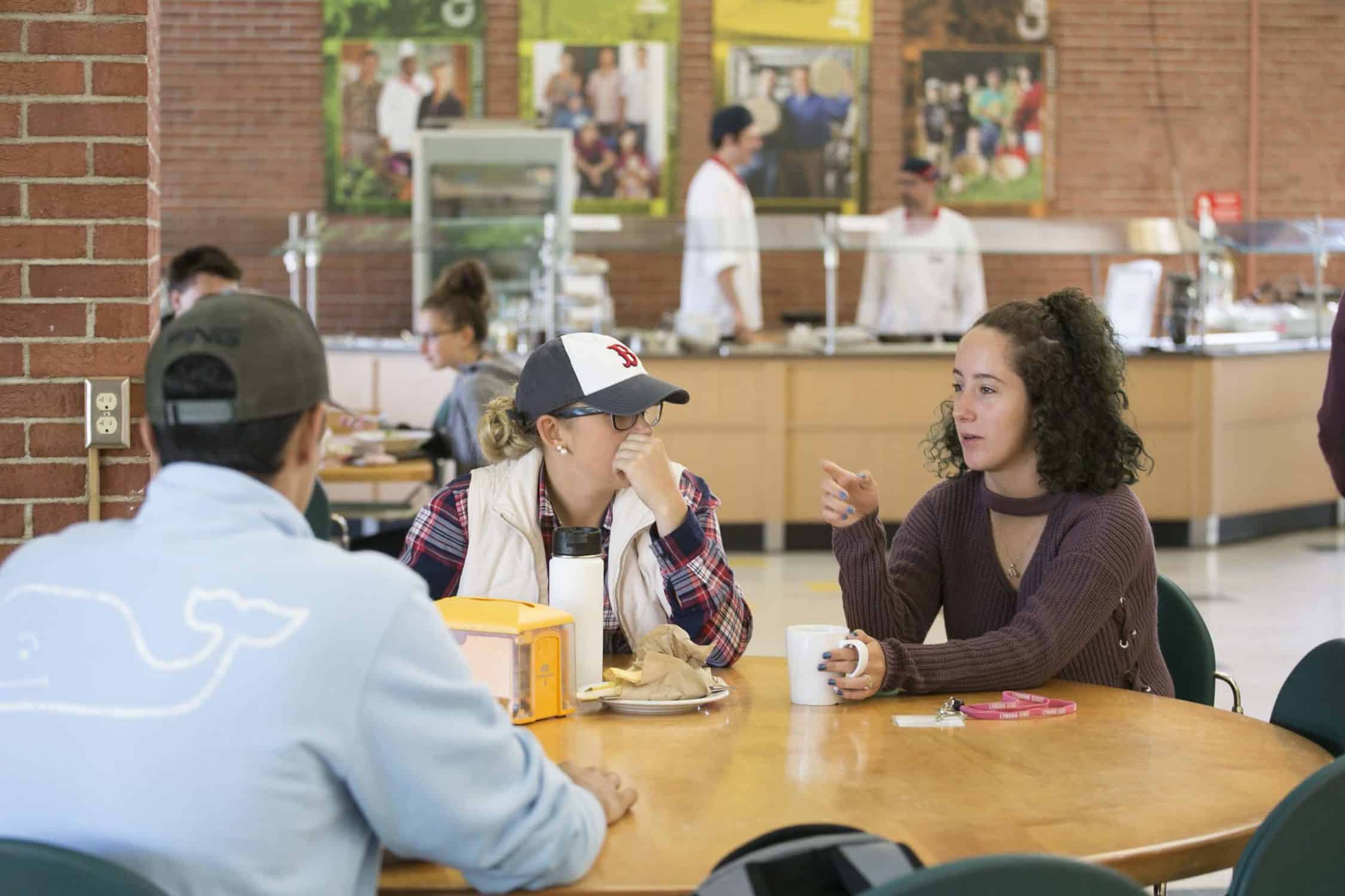 Students talk at a table in the dining hall on campus